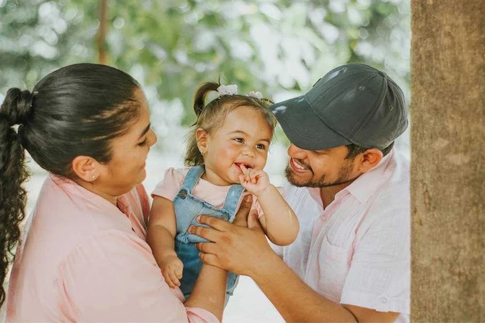 Indiana-Child-Support-Guidelines-2026–What-Hamilton-County-Parents-Need-to-Know-3 Smiling parents holding young daughter outdoors, showing family support and care in Indiana child custody.