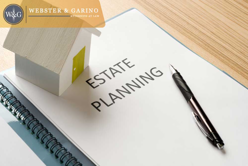 Estate planning folder with miniature house and pen representing Webster & Garino legal services