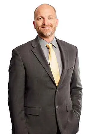 A smiling man in a suit and tie represents compassionate legal guidance at a trusted Indiana law firm.| Webster & Garino, LLC | Indiana Law Firm serving Hamilton County